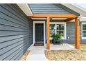 Welcoming entryway with a modern black door, wooden beam accents, a convenient bench, and attractive landscaping at 1161 Cr 443, Lake Panasoffkee, FL 33538