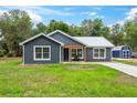 Inviting single-story house with gray siding, a metal roof, well kept lawn, and a matching storage shed in the backyard at 1161 Cr 443, Lake Panasoffkee, FL 33538