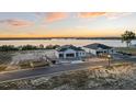 An aerial view showcases a neighborhood with waterfront property, new homes under construction, and beautiful sunset skies at 1548 Covey Rise Ter, Winter Haven, FL 33884