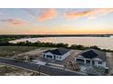 Aerial shot of lakeside neighborhood featuring new home construction near the water under orange and pink skies at 1548 Covey Rise Ter, Winter Haven, FL 33884