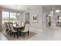 Elegant dining room featuring a stylish chandelier, large window, and tile floors at 136 Venetian Palms Blvd, New Smyrna Beach, FL 32168
