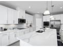 Modern kitchen with white cabinets, stainless steel appliances, and a large center island at 1204 Ivy Manor St, Minneola, FL 34715