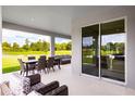 Covered patio with dining and lounge area, overlooking a lush green lawn and pond at 1204 Ivy Manor St, Minneola, FL 34715