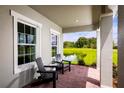 Covered front porch with brick flooring and black Adirondack chairs with a pond view at 1204 Ivy Manor St, Minneola, FL 34715