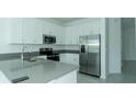 Modern kitchen featuring stainless steel appliances and bright white cabinets with gray countertops at 7433 Stone Creek Trl, Kissimmee, FL 34747