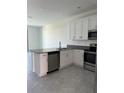Modern kitchen boasts stainless steel appliances, island, and white cabinetry at 7433 Stone Creek Trl, Kissimmee, FL 34747