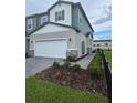 View of a two-story home showcasing its green siding, two-car garage, and nicely landscaped front yard at 2453 Magnolia Reserve Rd, Ocoee, FL 34761