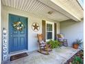 Inviting front porch with rocking chairs and a blue front door with decorative wreath and 'Welcome' sign at 12396 Sw 64Th Street Rd, Ocala, FL 34481