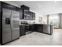 Modern kitchen features stainless steel appliances, dark cabinets, granite countertops, and a convenient breakfast bar at 1196 Port Blue Way, Lady Lake, FL 32159