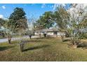 Spacious front yard with mature trees surrounding a cozy, one-story home, creating a peaceful setting at 4851 Ne 7Th St, Ocala, FL 34470