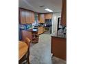 Well-lit kitchen with wooden cabinetry, stainless steel appliances, and a built-in shelving unit at 11301 Huggins St, Leesburg, FL 34788