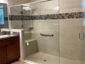 Modern bathroom with a tiled shower, a glass door, a built-in seat, and a grab bar at 803 Jasmine Creek Rd, Kissimmee, FL 34759