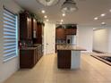 Spacious kitchen with an island, tile floors, granite counters, stainless appliances, and dark wood cabinets at 803 Jasmine Creek Rd, Kissimmee, FL 34759
