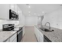 Kitchen with white cabinets, granite countertops, stainless steel appliances, and grey tile floors at 1129 Red Buckeye Ct, Deland, FL 32720