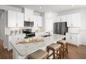 Modern kitchen featuring white cabinets, stainless steel appliances, and a large island with granite countertops and bar stool seating at 6408 Domizio Dr, Winter Haven, FL 33884
