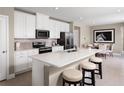 Modern kitchen boasts white cabinetry, stainless steel appliances, and an island with bar seating at 6509 Domizio Dr, Winter Haven, FL 33884