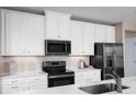 Bright kitchen with white cabinets, stainless steel appliances, granite countertops, and a modern backsplash at 6528 Domizio Dr, Winter Haven, FL 33884
