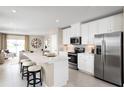 Modern kitchen with stainless steel appliances, center island with barstool seating and an open-concept to the living area at 6528 Domizio Dr, Winter Haven, FL 33884