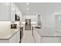 Modern kitchen features stainless steel appliances, granite countertops, and bright white cabinets at 5285 Luisa Ct, St Cloud, FL 34771