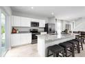 Bright, modern kitchen featuring stainless steel appliances, granite counters, island with bar seating, and tile floors at 1203 Port Blue Way, Lady Lake, FL 32159
