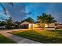 Inviting home exterior is accentuated by manicured lawn and warm lighting at twilight at 7289 Lake Floy Cir, Orlando, FL 32819