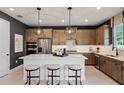 Modern kitchen with stylish lighting, stainless steel appliances, an island, and barstool seating at 847 Emerald Grove Dr, Apopka, FL 32703