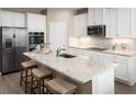 Kitchen island with stainless steel appliances, seating, and modern fixtures at 10899 Sw 73Rd Ct, Ocala, FL 34476