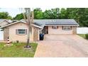 Inviting single-story house showcasing a brick driveway, stone accents, and efficient solar panels at 774 Hendrix Ave, Orlando, FL 32825