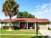 Tan house with red roof, palm tree, and landscaped lawn at 11432 Cardiff Dr, Orlando, FL 32837