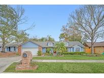 Charming single-story home featuring a blue exterior, well-manicured lawn and landscaped garden at 8847 Rose Hill Dr, Orlando, FL 32818