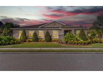 Charming single-story home featuring manicured landscaping, stone accents, and a neutral color palette at sunset at 1532 Eagle Ridge Dr, Lakeland, FL 33813