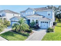 Two-story house with light blue exterior, stone accents, and a three-car garage at 1457 Olympic Club Blvd, Champions Gate, FL 33896