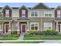 Two-story townhome with gray siding, red shutters, and a manicured lawn at 688 Orange Belt Loop, Winter Garden, FL 34787