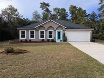 Single-story house with a gray exterior, light-colored garage, and a small front yard at 15900 Sw 19Th Avenue Rd, Ocala, FL 34473