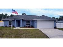 Newly built home with blue exterior, white fence, and a two-car garage at 12854 Sw 77Th Cir, Ocala, FL 34473