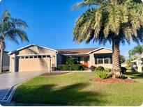 House exterior featuring a two-car garage and manicured lawn at 457 Enright Pl, The Villages, FL 32162