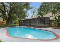 Inviting kidney-shaped pool with brick coping, screened patio, and lush landscaping at 4539 Wild Rose Ct, Orlando, FL 32808