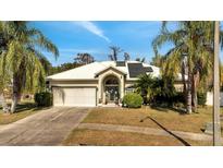 Charming single-story home featuring lush landscaping, a two-car garage, and solar panels at 603 Pinehurst Ct, Kissimmee, FL 34758