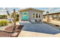 Charming single-story home featuring a light gray exterior, bright turquoise door, and well-maintained landscaping at 9000 Us Highway 192 # 242, Clermont, FL 34714