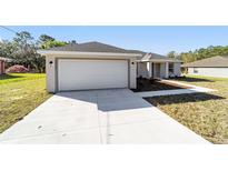 Modern home featuring a two-car garage and a well-manicured lawn at 20184 Sw 57 St, Dunnellon, FL 34431