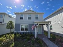 Charming two-story home with a covered entryway, landscaped yard, and an American flag for added curb appeal at 10959 Vesper Aly, Orlando, FL 32829
