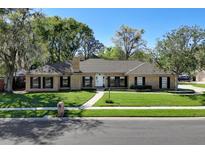 Charming brick home featuring a manicured lawn, mature trees, and a welcoming walkway to the front door at 410 Spring Valley Ln, Altamonte Springs, FL 32714
