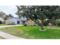 Charming single-story home featuring stone accents, a well-manicured lawn, and mature landscaping at 1776 E Cheryl Dr, Winter Park, FL 32792