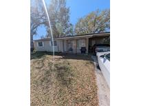 Modest single-story home with covered parking and a front porch amidst trees at 5195 Edwina St, Orlando, FL 32811