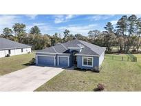 Charming single-story home featuring a three-car garage, well-maintained lawn, and mature trees in a tranquil setting at 11331 Sw 54Th Cir, Ocala, FL 34476