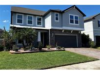Charming two-story home features a well-manicured lawn, stone accents, and a two-car garage at 14160 Dove Hollow Dr, Orlando, FL 32824