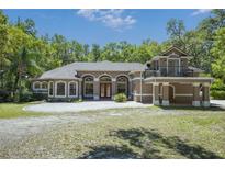 Stunning two-story home with arched windows, red door, balcony, and a circular driveway at 445 Se 98Th Ave, Webster, FL 33597