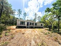 New home exterior, showing grey siding, black shutters, and an unfinished front yard at 9124 Sw 158Th Ln, Dunnellon, FL 34432