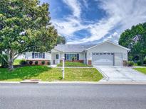 Charming single-story home with a well-manicured lawn, mature trees, and a two-car garage, perfect for suburban living at 13729 Se 89Th Ave, Summerfield, FL 34491