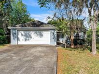 Charming single story home with blue siding, attached garage, and mature landscaping at 1606 Center St, Deland, FL 32720
